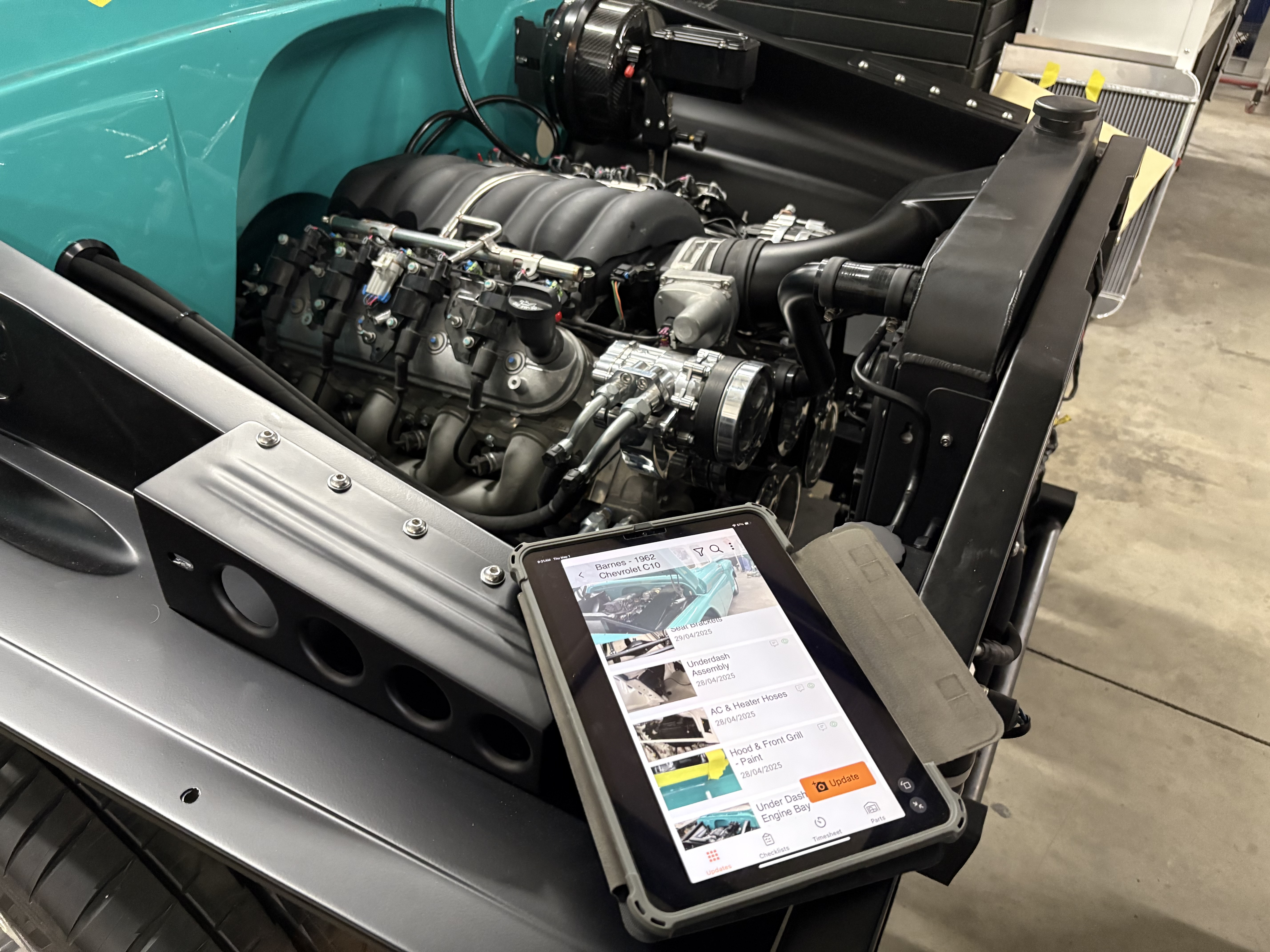GlobalWorkshop project updates shown on a tablet alongside the 1962 Chevrolet C10 engine installation